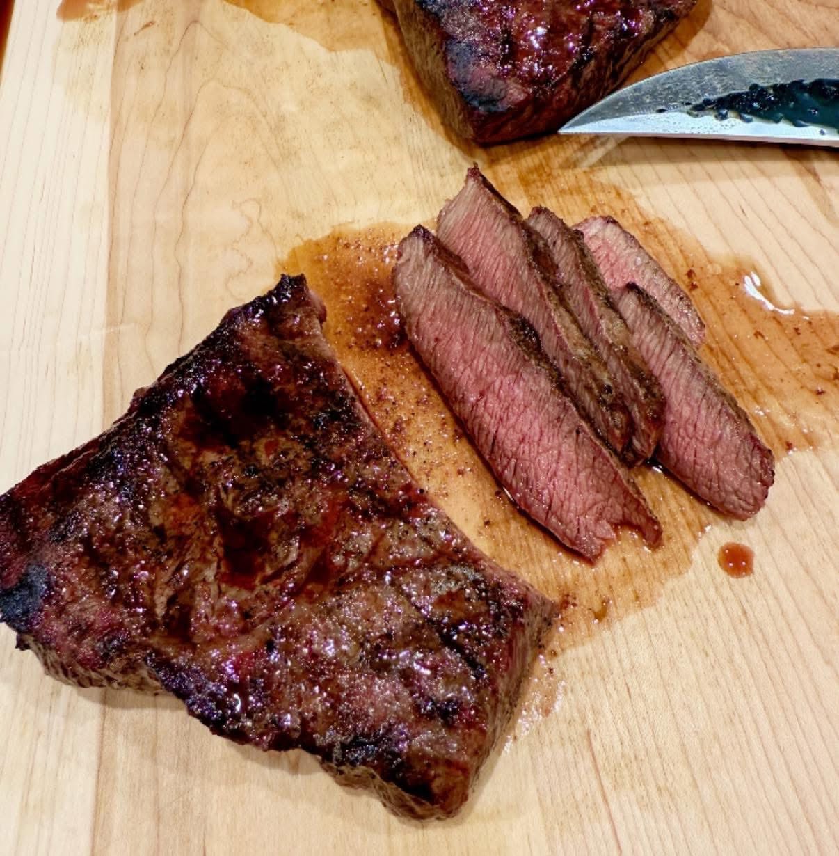 Seared and sliced Wagyu steak resting on a wooden cutting board