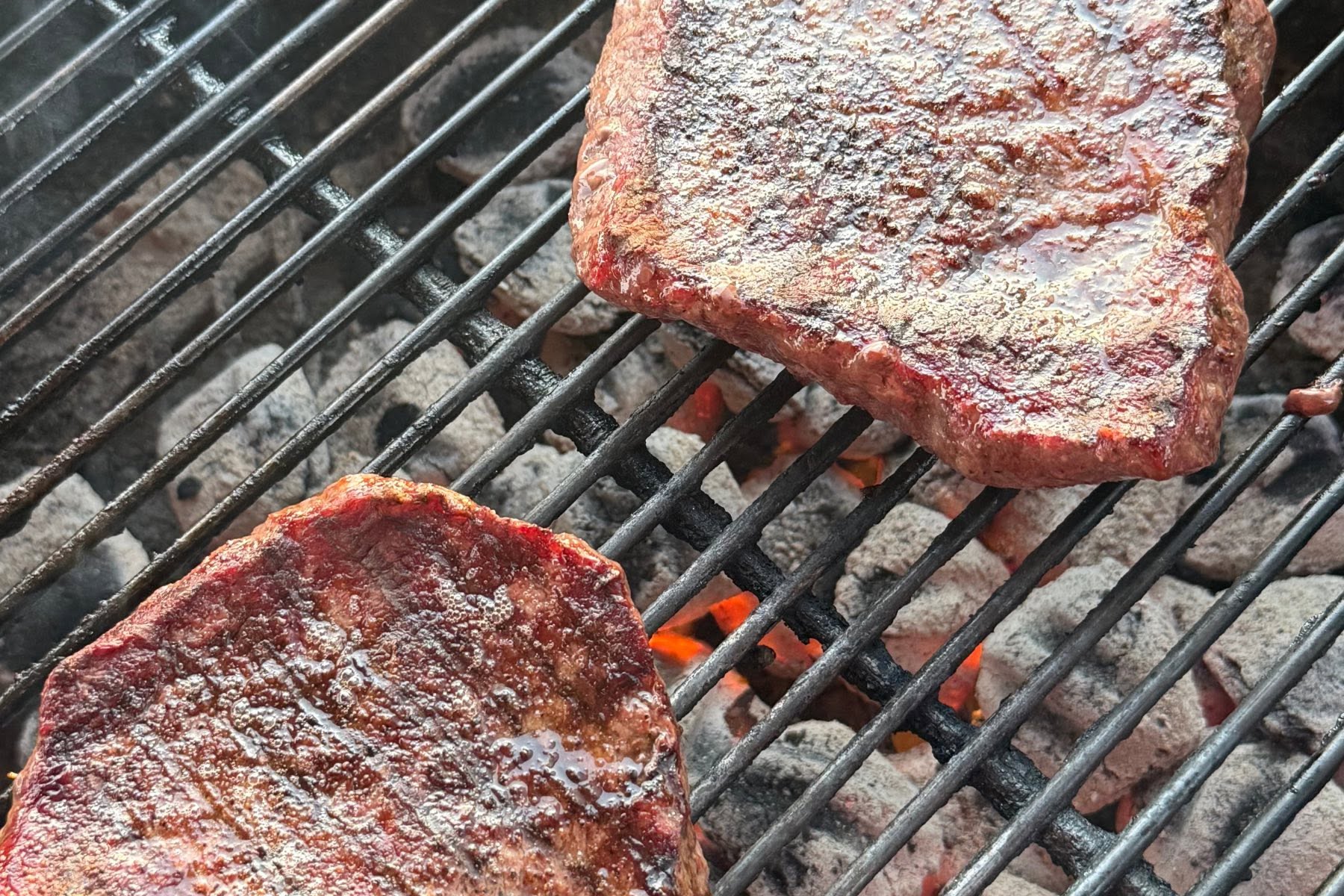 Wagyu steaks searing on a charcoal grill